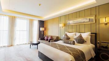 Habitación de hotel con una cama grande, un sofá, una mesita y un televisor de pared.