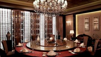 A round dining table with chairs, a chandelier, and a view of a mountainous landscape through the window.