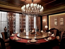 A round dining table with chairs, a chandelier, and a view of a mountainous landscape through the window.