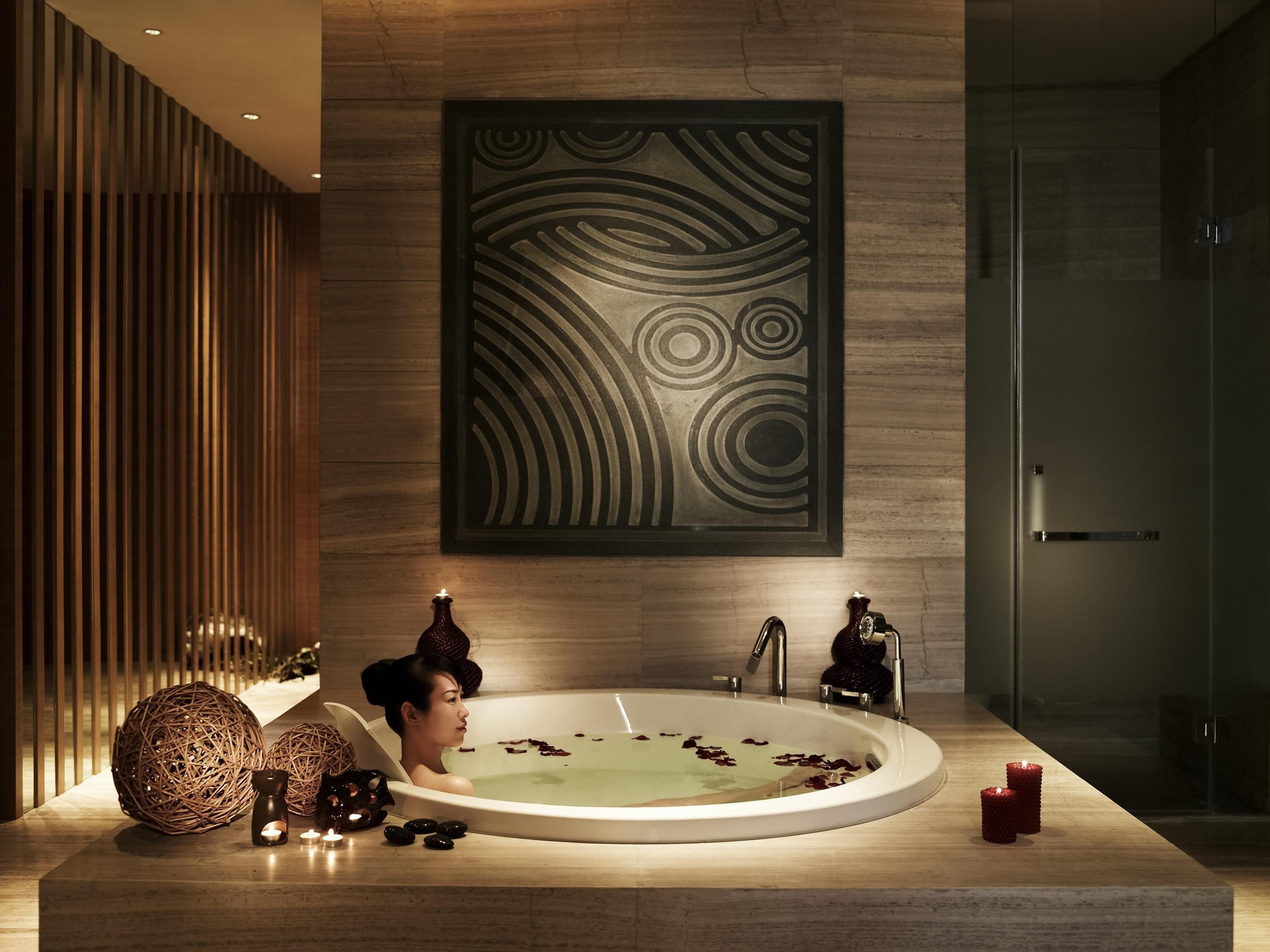 A modern bathroom with a freestanding bathtub, decorative elements, and a large wall art piece.