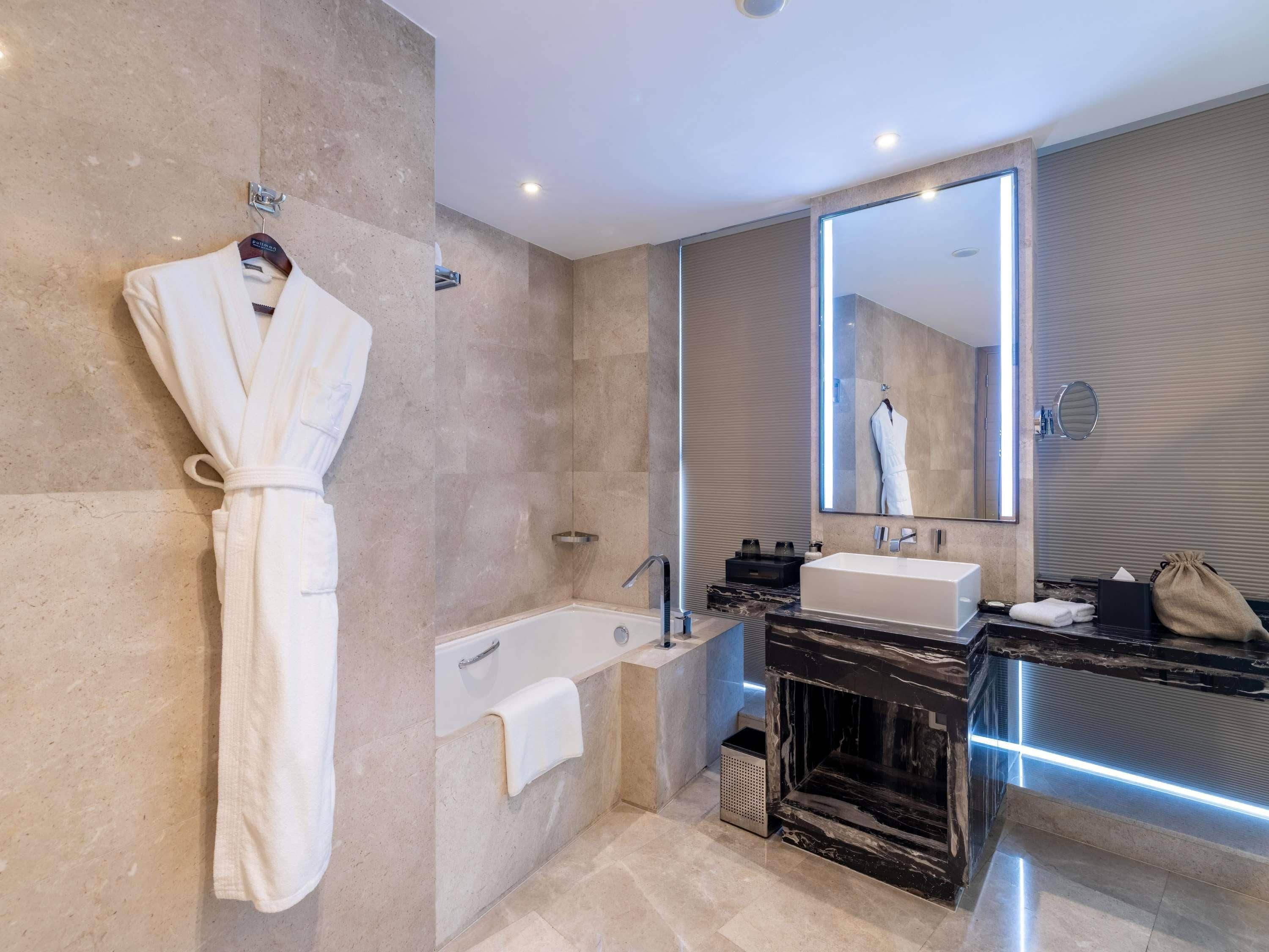 Un baño moderno con una bañera, un espejo grande y una bata colgada en la pared.