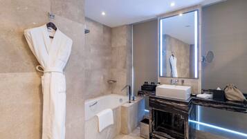 Un baño moderno con una bañera, un espejo grande y una bata colgada en la pared.