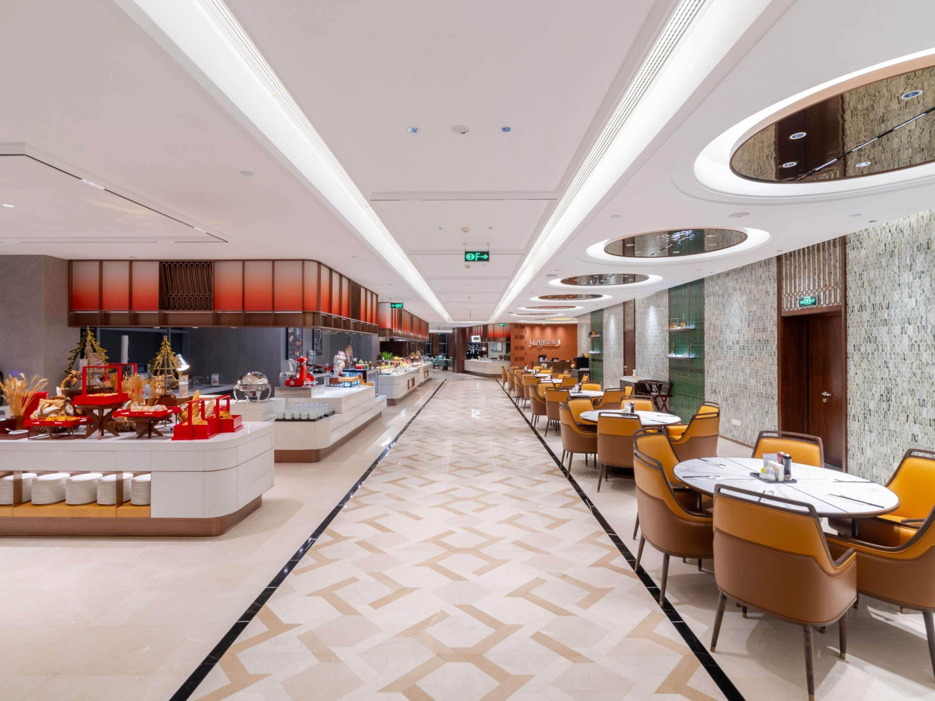 A modern hotel lobby with a central reception desk, seating area, and a decorative Christmas tree display.