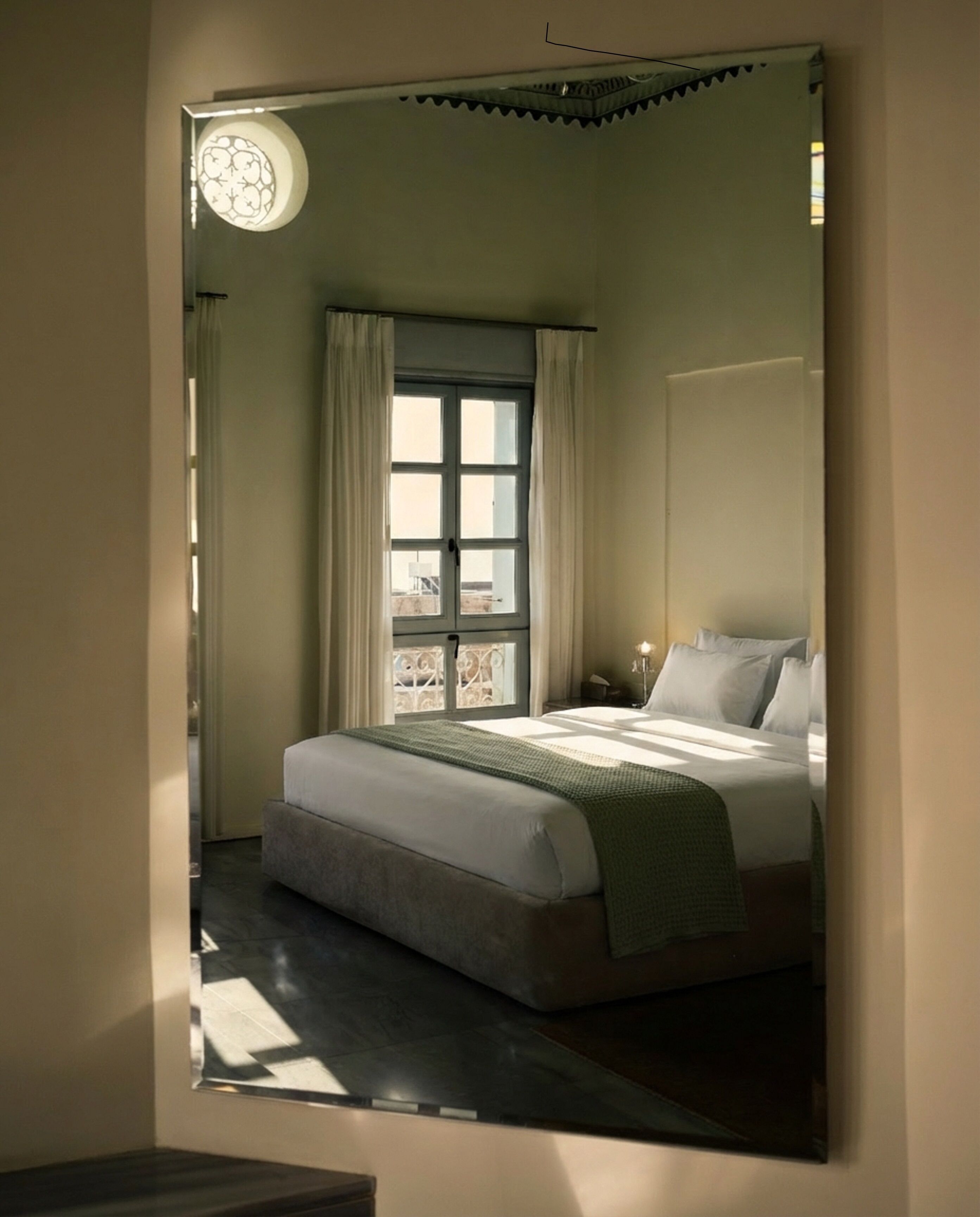 A bedroom with a bed, curtains, a window, and a wall-mounted light fixture.
