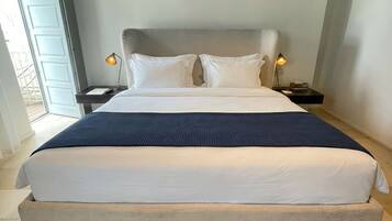 A large bed with a headboard, two bedside lamps, and a patterned rug.