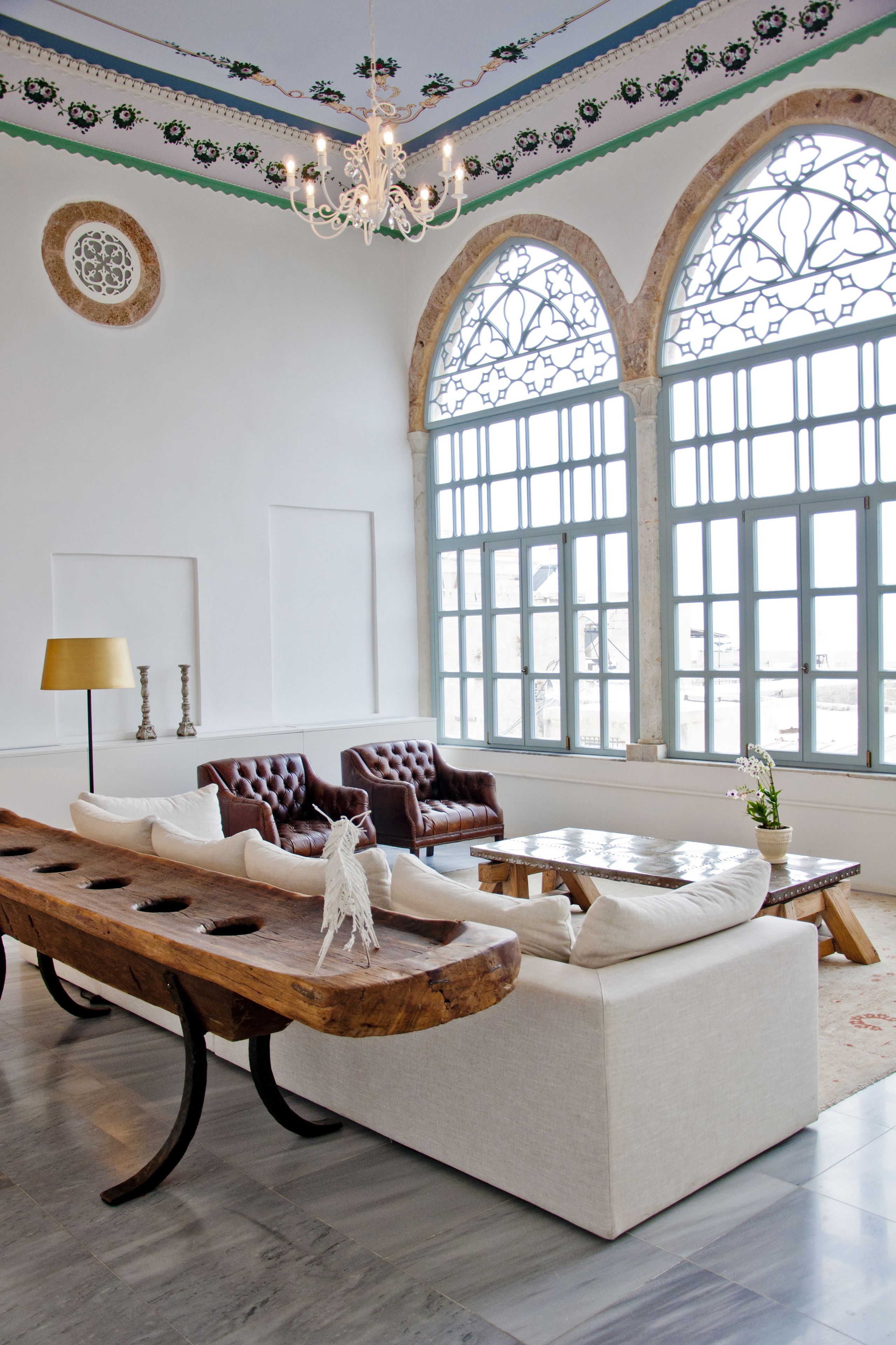 Un salón amplio con un sofá grande, dos sillones, una mesa de centro de madera y una araña.