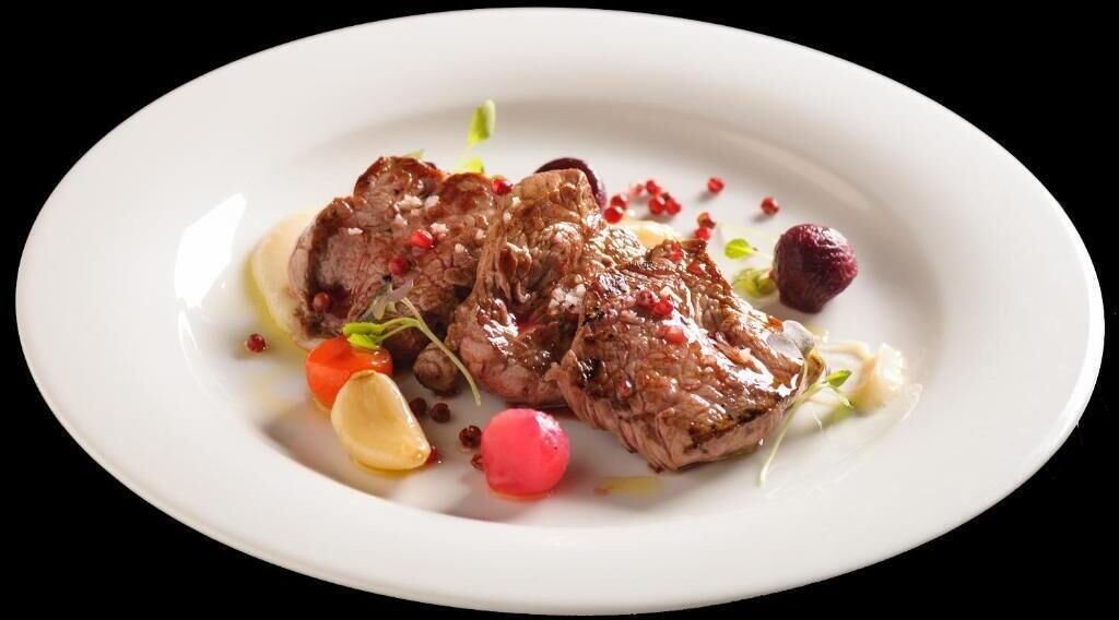 Un plato de carne con verduras y salsa.