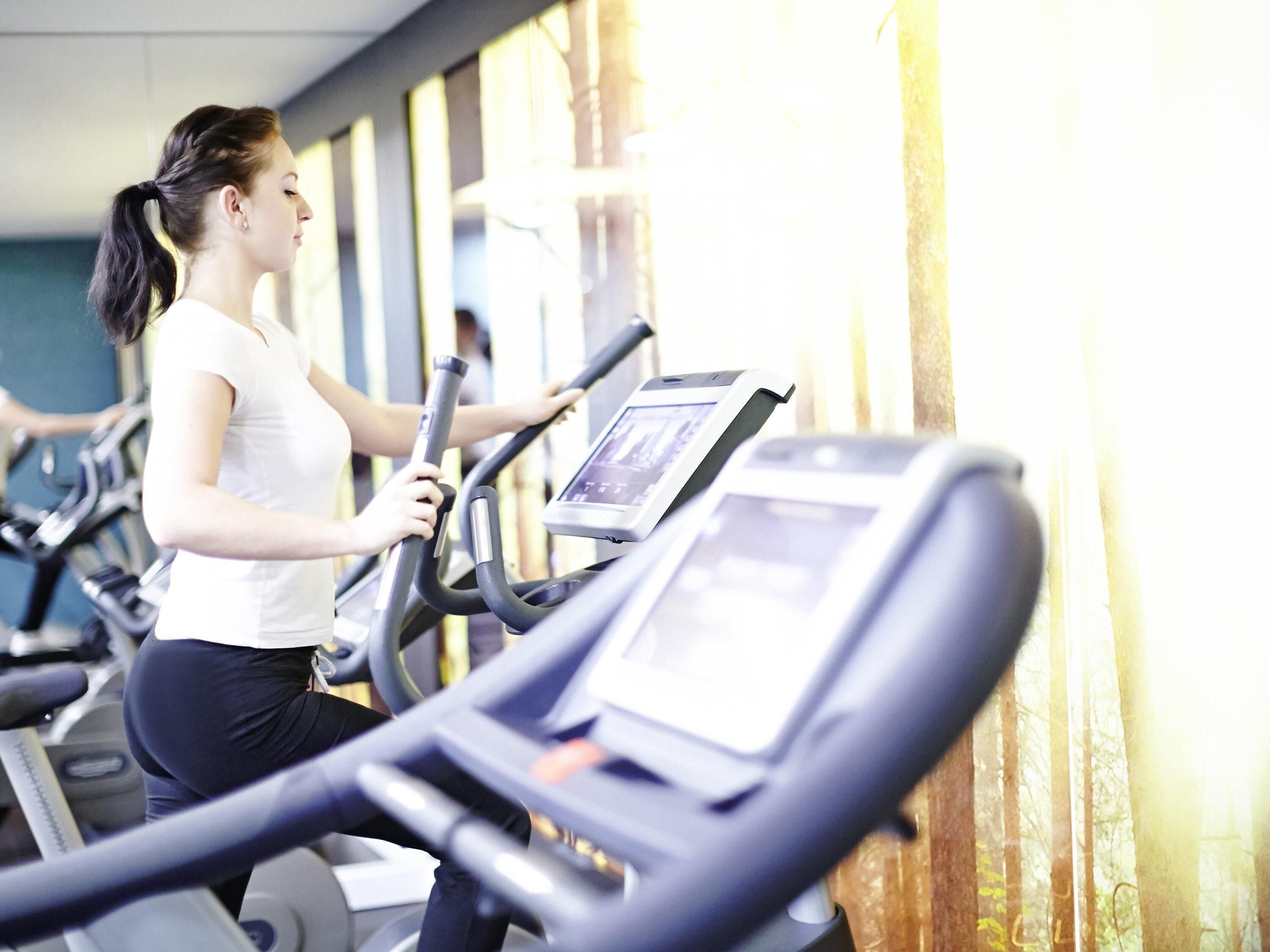 Ein Fitnessstudio mit Laufbändern und einer Person, die eines benutzt.