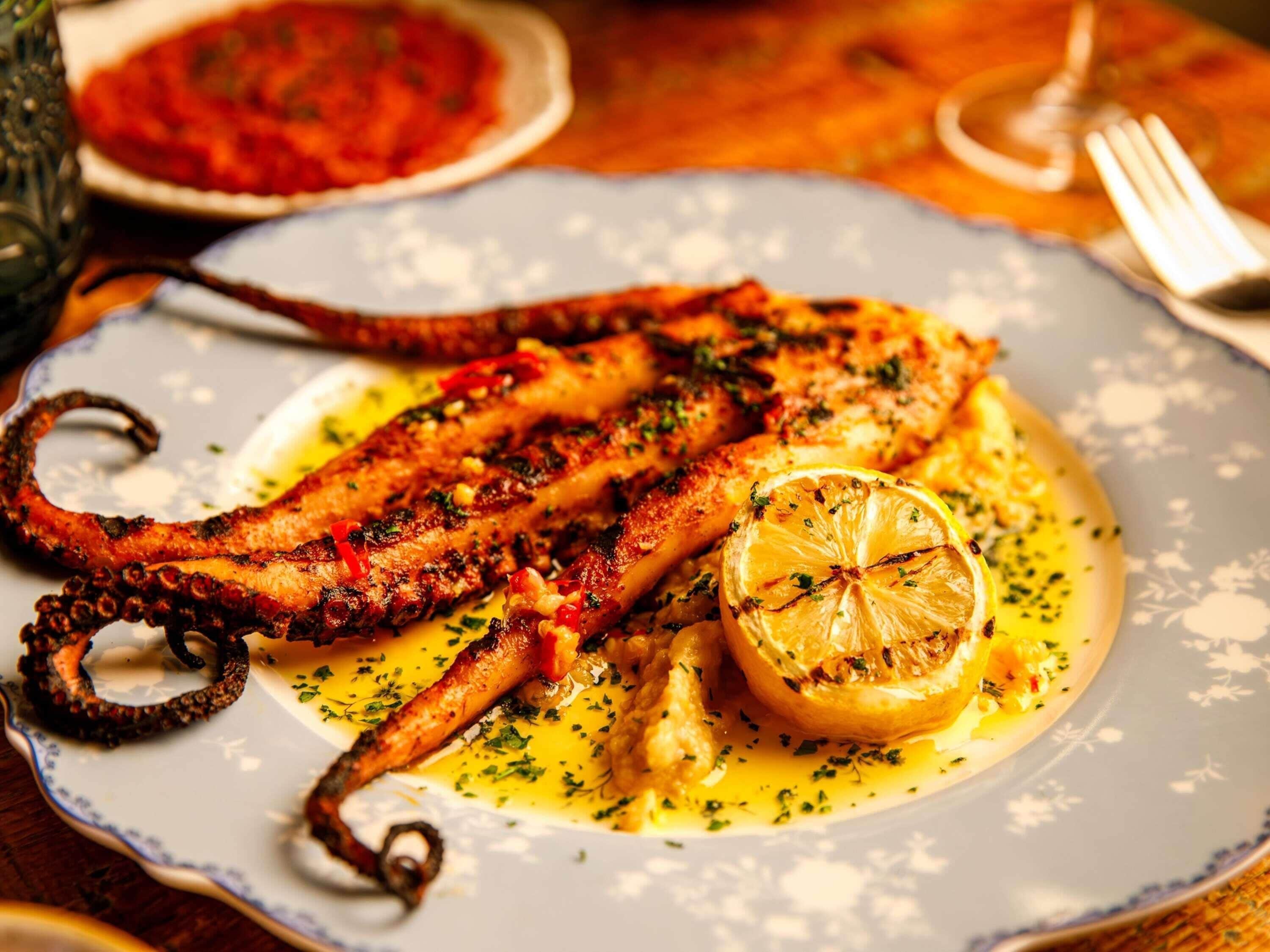 A plate of grilled octopus with lemon and herbs.