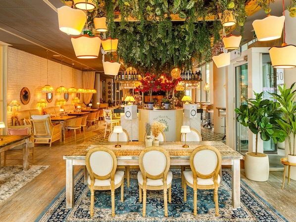 A restaurant with a bar area, wooden furniture, and hanging plants.