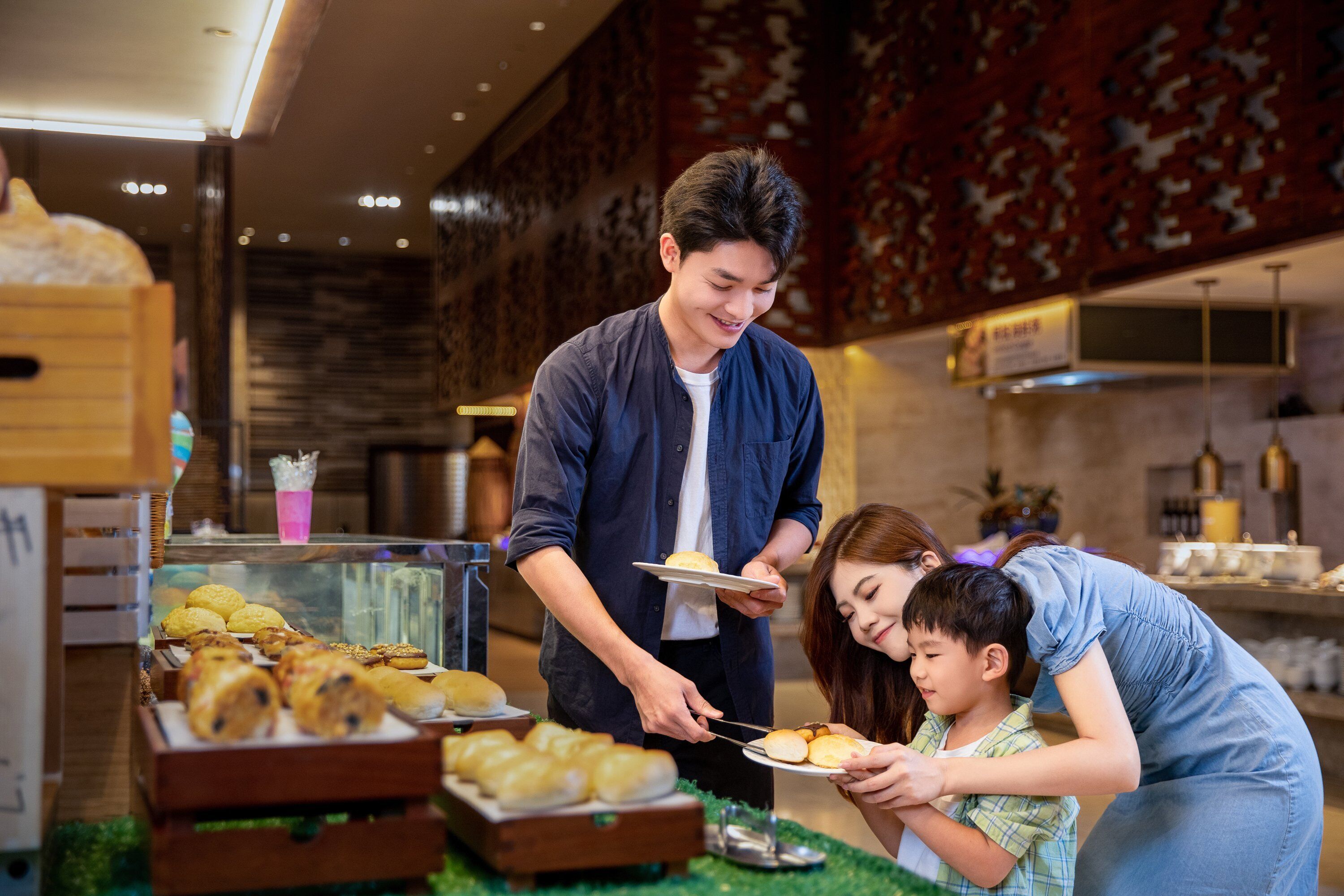 Un espace buffet proposant diverses pâtisseries et une personne chargée de servir les plats.