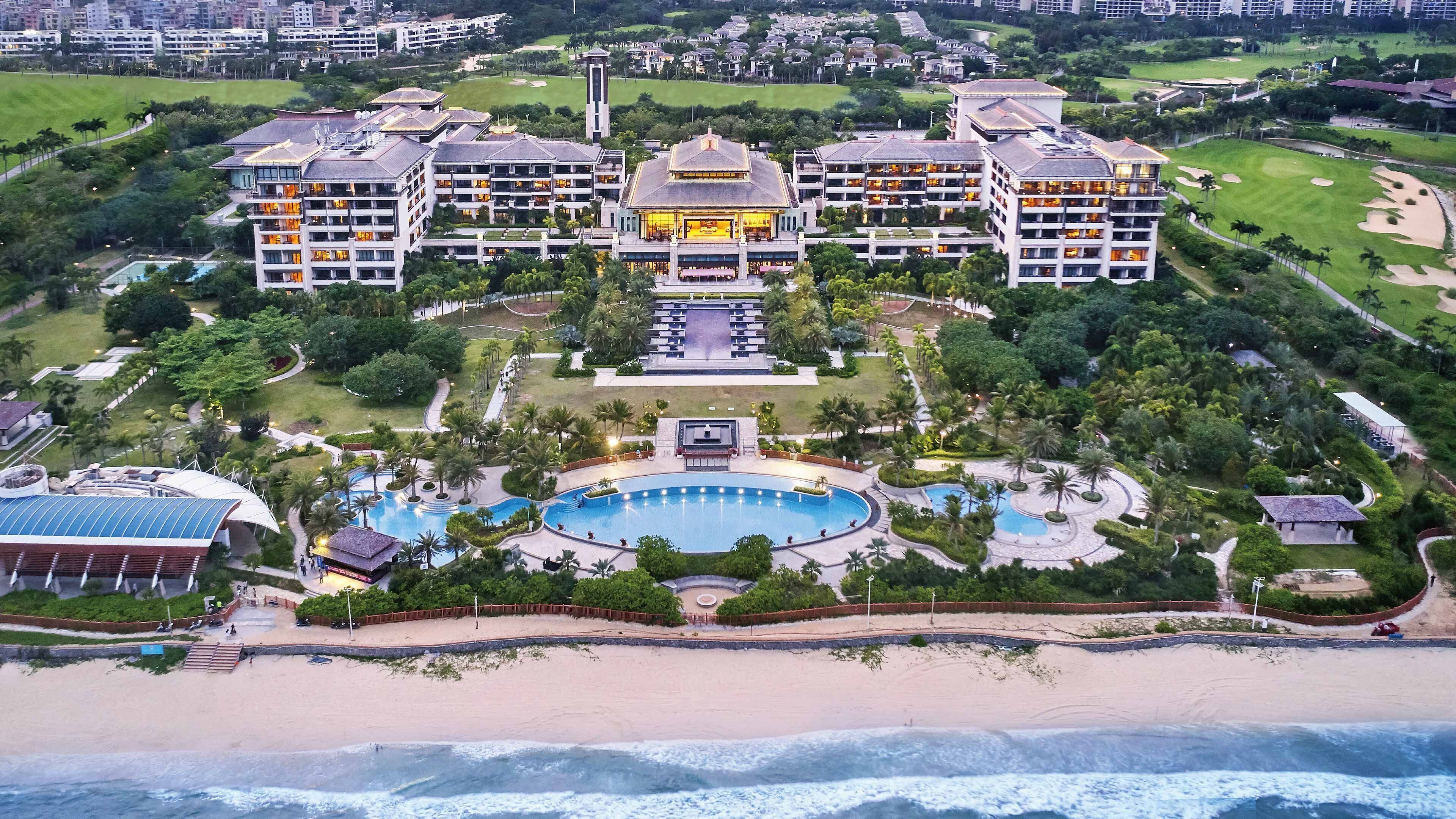 A resort with multiple buildings, a central pool, and a beachfront.