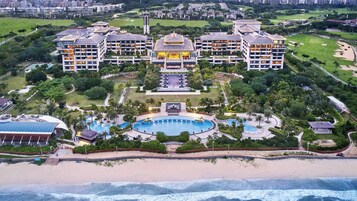 A resort with multiple buildings, a central pool, and a beachfront.