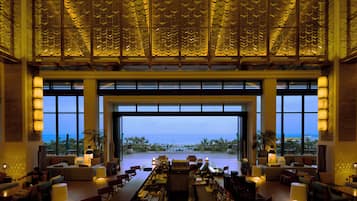 A spacious lobby with a large open doorway leading to a terrace with a view of the sea.