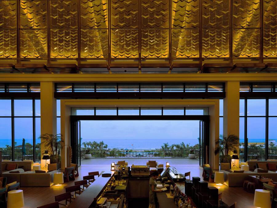 A spacious lobby with a large open doorway leading to a terrace with a view of the sea.