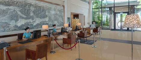 A reception area with a receptionist, computers, and a large window with a view of greenery.