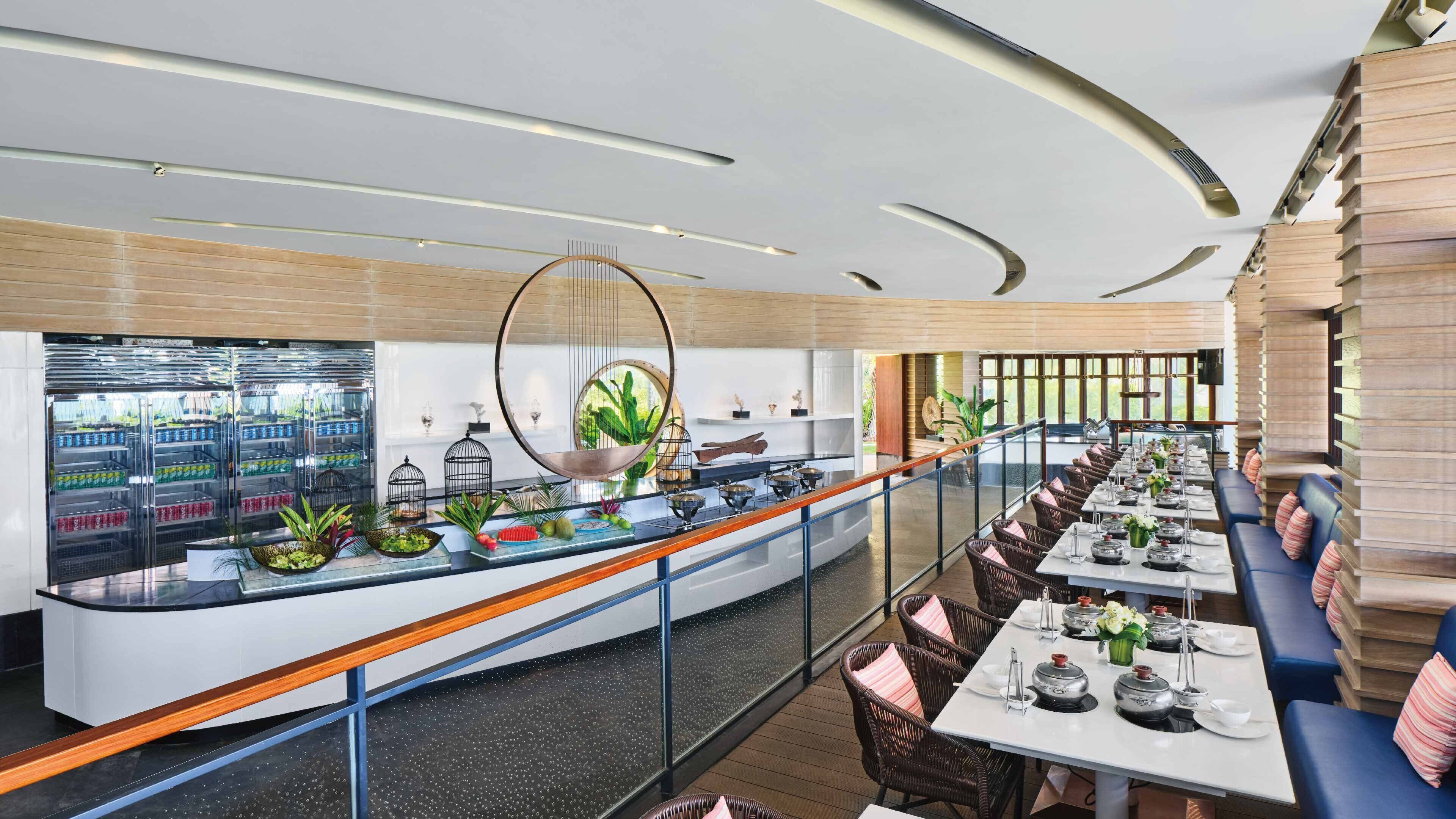 Un restaurante moderno con una barra larga, zona de estar y vistas al exterior.