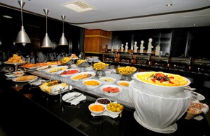 Un buffet proposant une variété de plats et un grand saladier rempli de fruits.