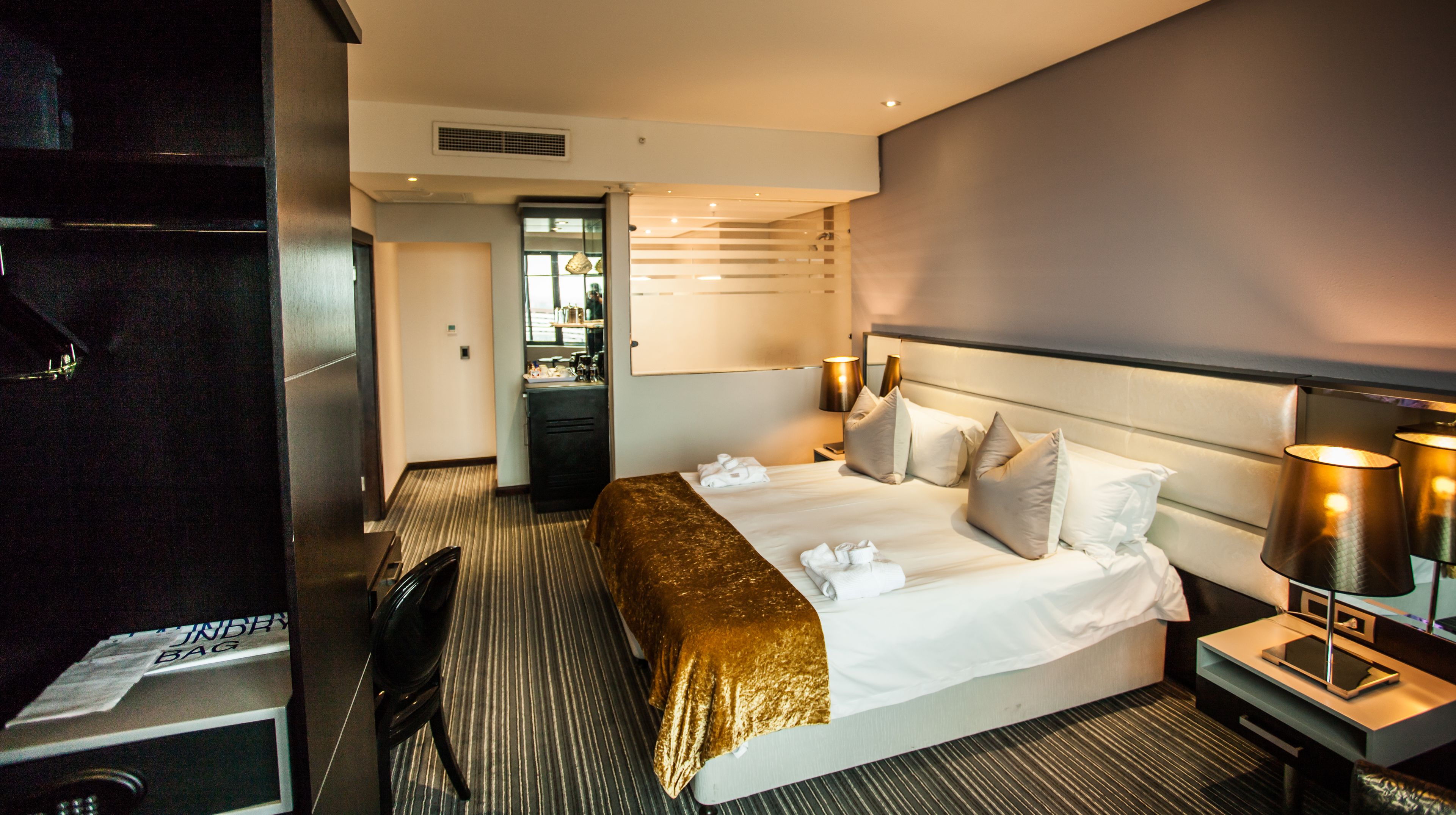 A hotel room with a large bed, a desk, a chair, and a minibar.