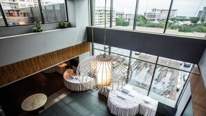 Un interior moderno con techo alto, ventanas amplias y una lámpara colgante en el centro.