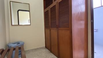 Una habitación con un armario de madera, un espejo y una cesta de ropa.