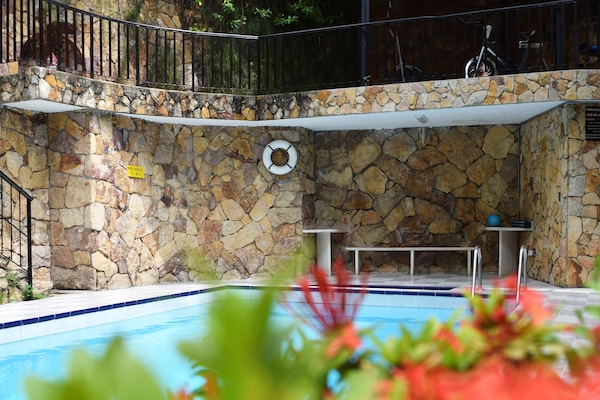 Una piscina al aire libre, sombrillas, sillones reclinables de piscina