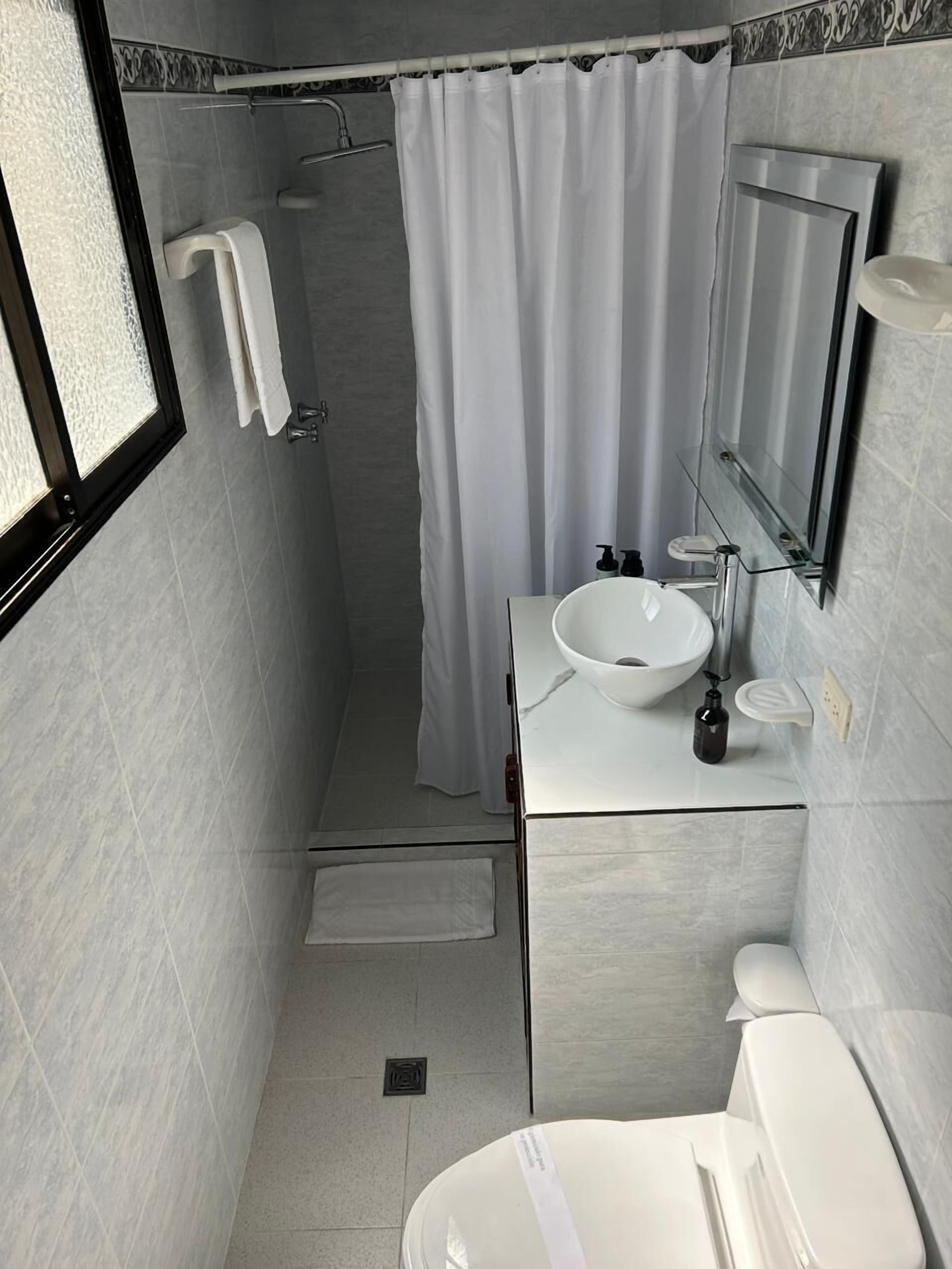 A modern bathroom with a white sink, a large mirror, and a shower area.