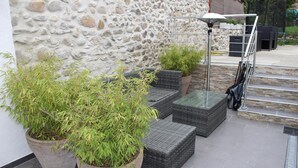 Uma área de pátio com paredes de pedra, móveis de exterior e plantas em vasos.
