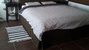 Quarto com uma cama grande, duas mesas de cabeceira, uma luminária em cada uma, um edredom estampado e um tapete listrado.