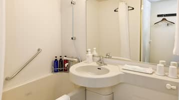 A modern bathroom with a bathtub, a sink, a toilet, and a mirror.