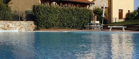 Een buitenzwembad, parasols bij het zwembad en ligstoelen