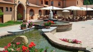 Un patio con una fuente, mobiliario exterior y una estatua.