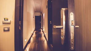 A hotel hallway with a wooden door, a light switch, and a wall-mounted intercom. - Hostal Prado (Madrid)