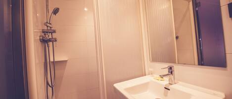 A bathroom with a shower, a sink, and a mirror.