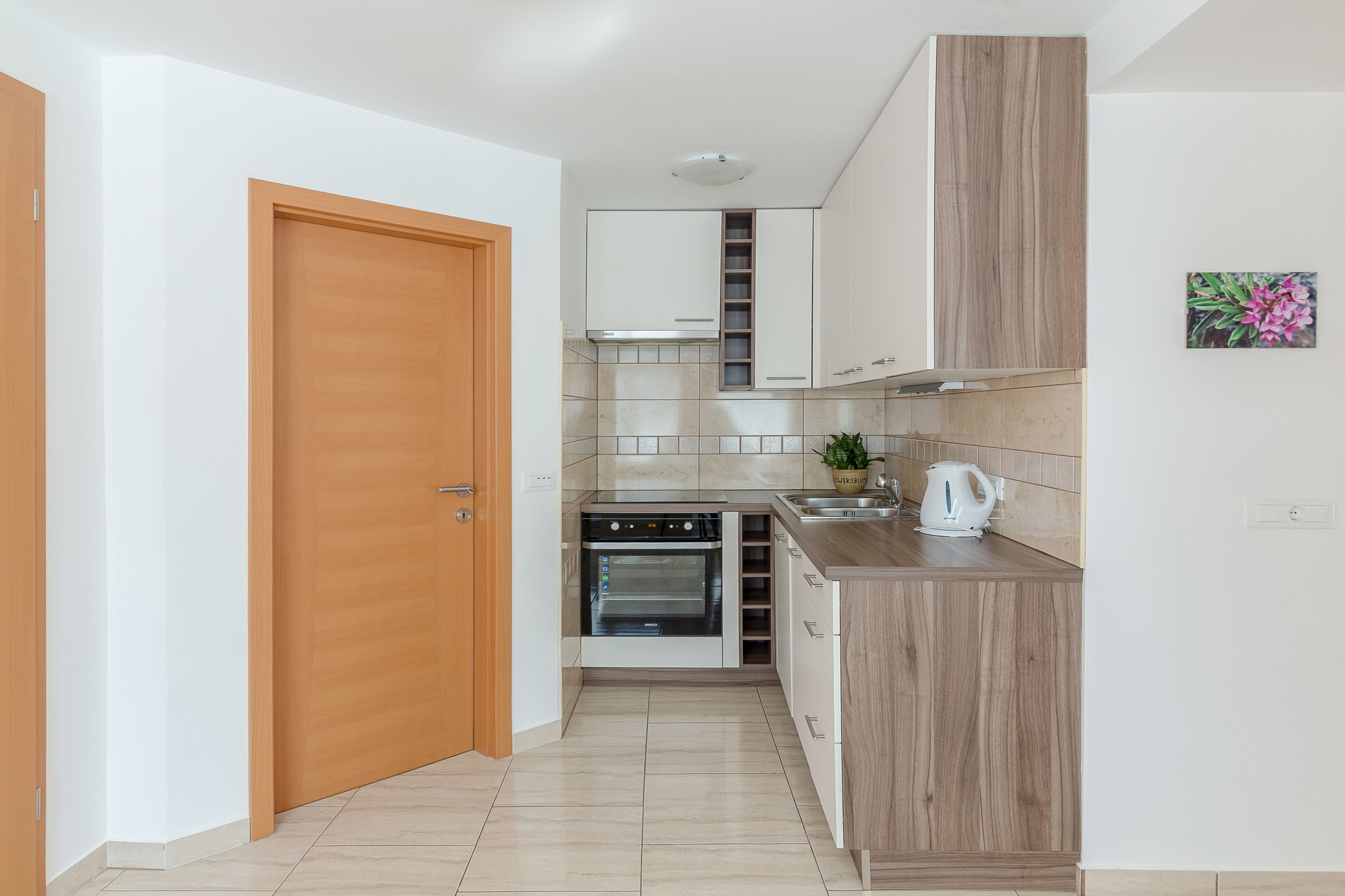 A compact kitchen with a built-in oven, a sink, and wooden cabinets.