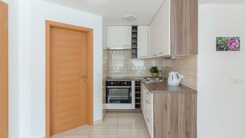 A compact kitchen with a built-in oven, a sink, and wooden cabinets.