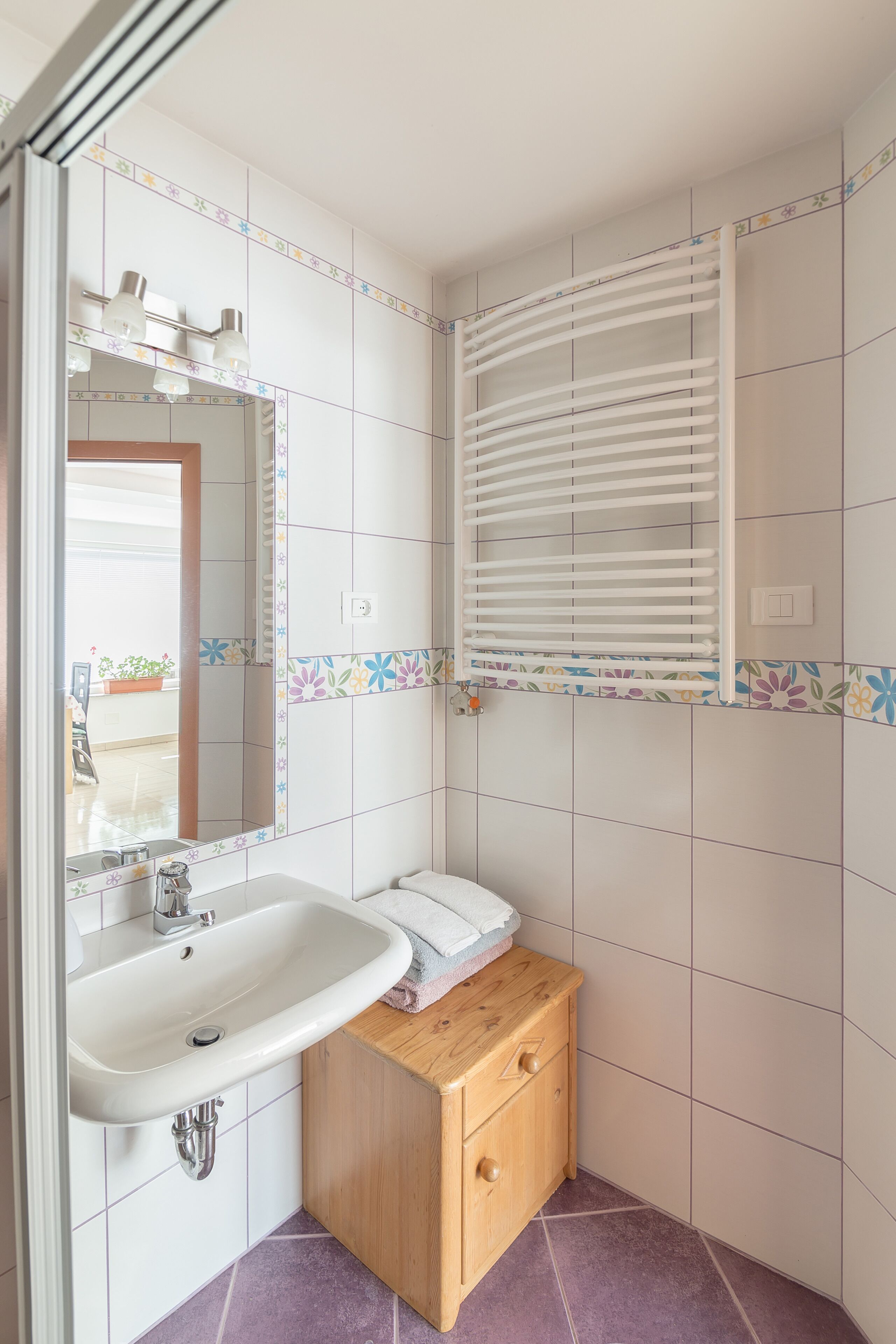 A bathroom with a white sink, wooden cabinet, and a mirror.