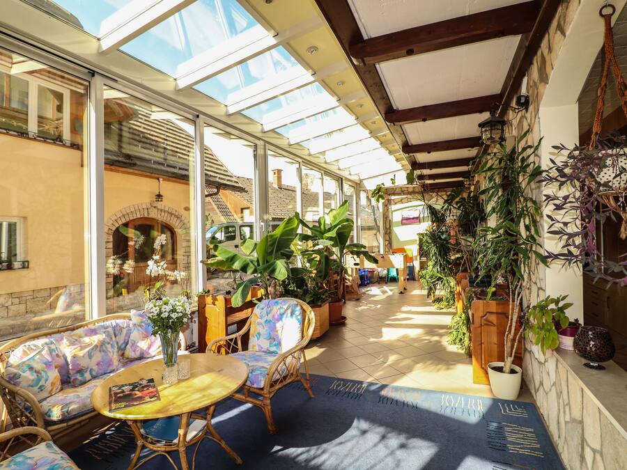 A sunlit patio with wicker furniture, potted plants, and a stone fireplace.