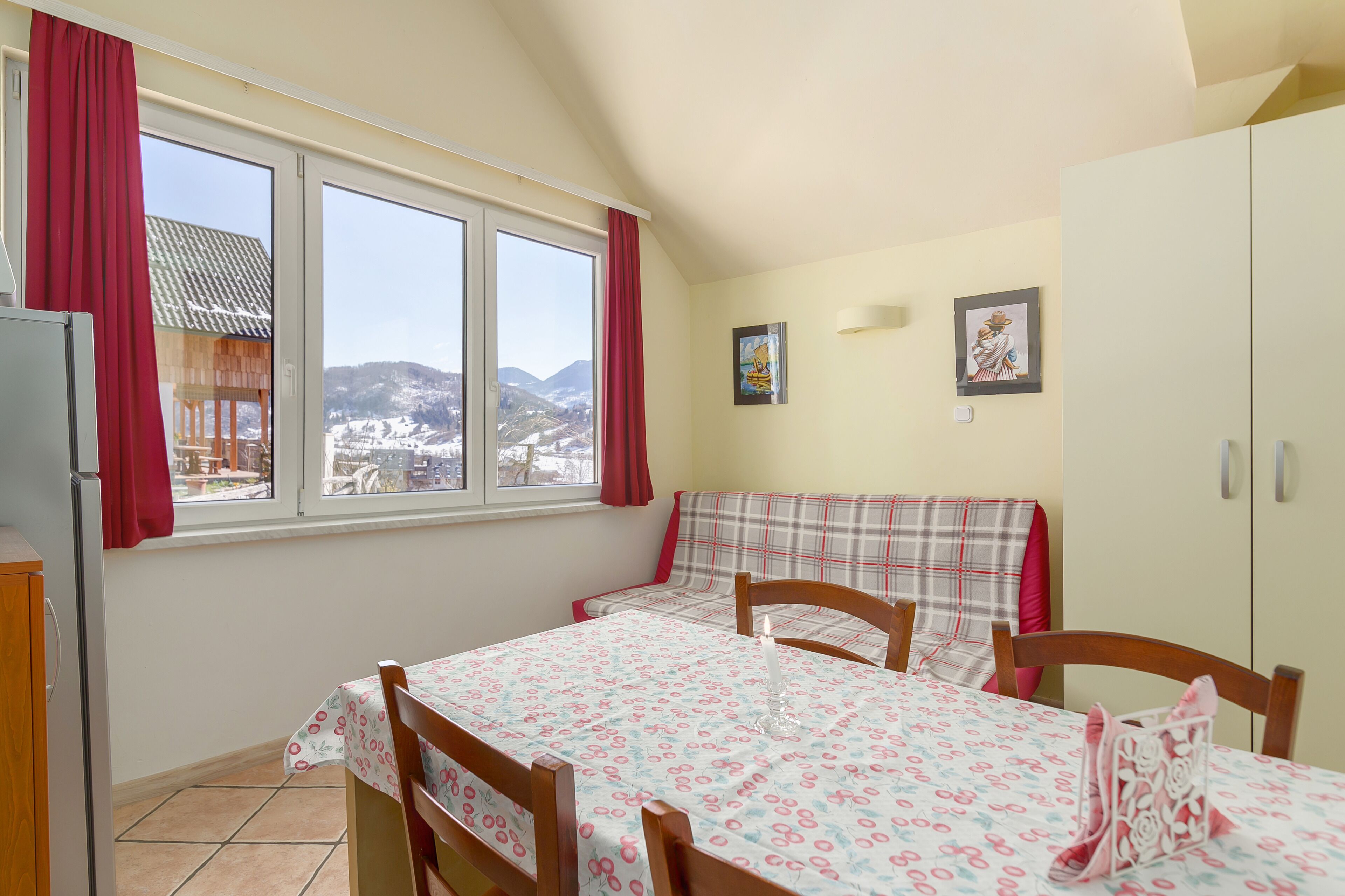 Un'accogliente zona pranzo con un tavolo apparecchiato per due, una panca e vista su un paesaggio innevato attraverso ampie finestre.