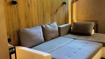 Ein modernes Schlafzimmer mit einer eingebauten Schlafcouch, Holzwandverkleidung und einem kleinen Fenster.