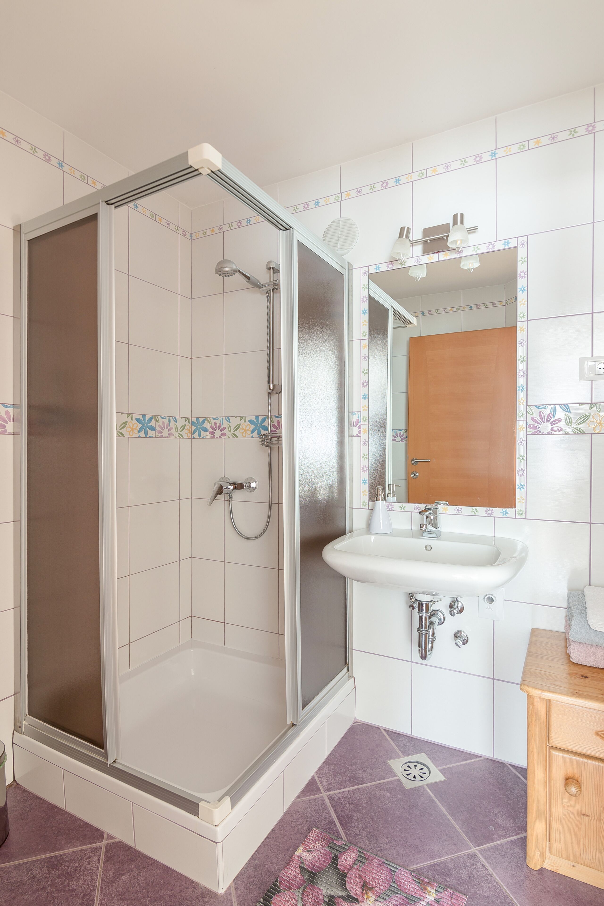 Une salle de bain avec une douche, un lavabo et un miroir.
