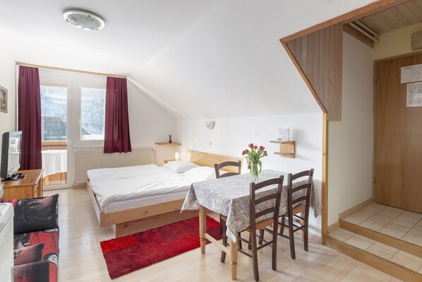 A bedroom with a bed, bedside table, lamp, and a small table with chairs. - Apartment house Jager (Bohinj)