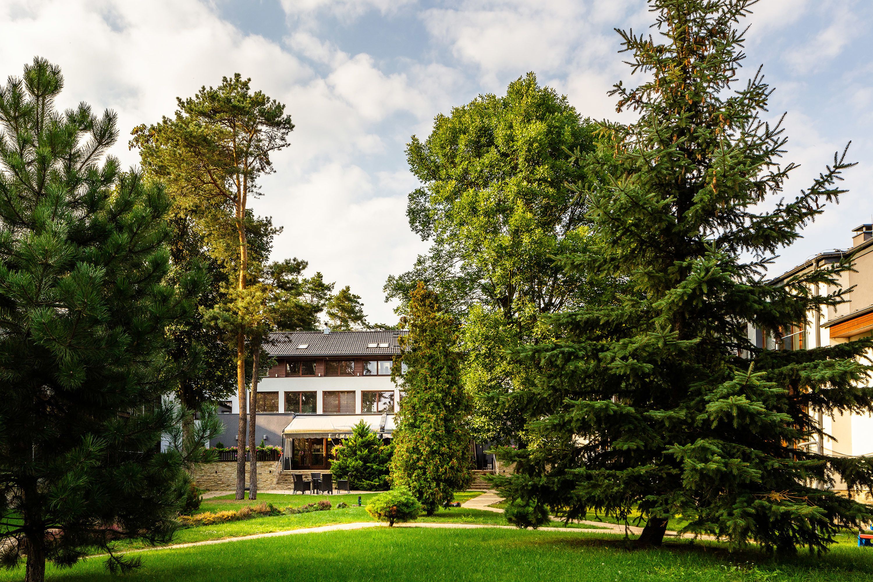 A modern building with a flat roof, surrounded by a well-maintained lawn and several large trees.