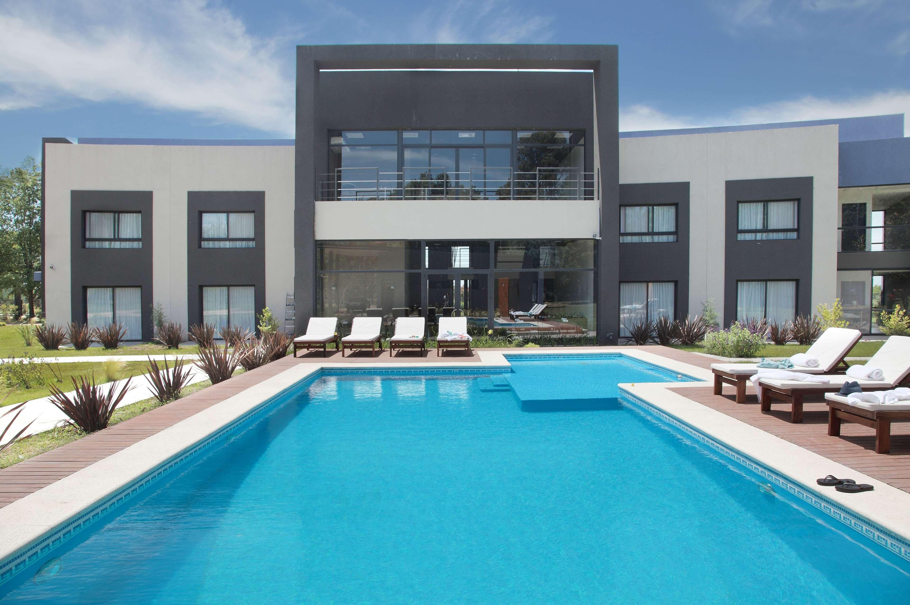 Ein modernes Gebäude mit Pool, Liegestühlen und blauem Himmel.