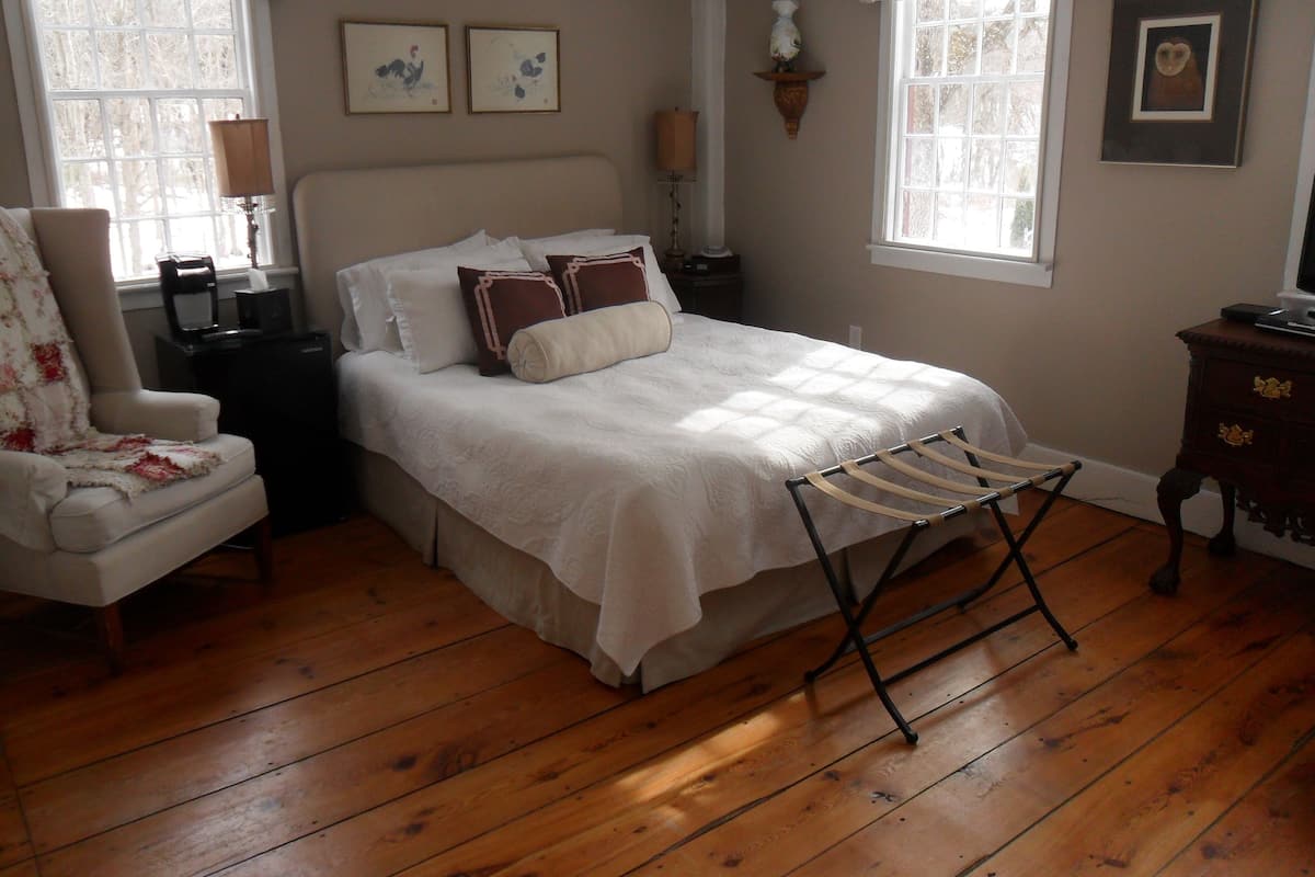 Quarto com uma cama grande, uma cadeira, uma mesa de cabeceira e um armário.