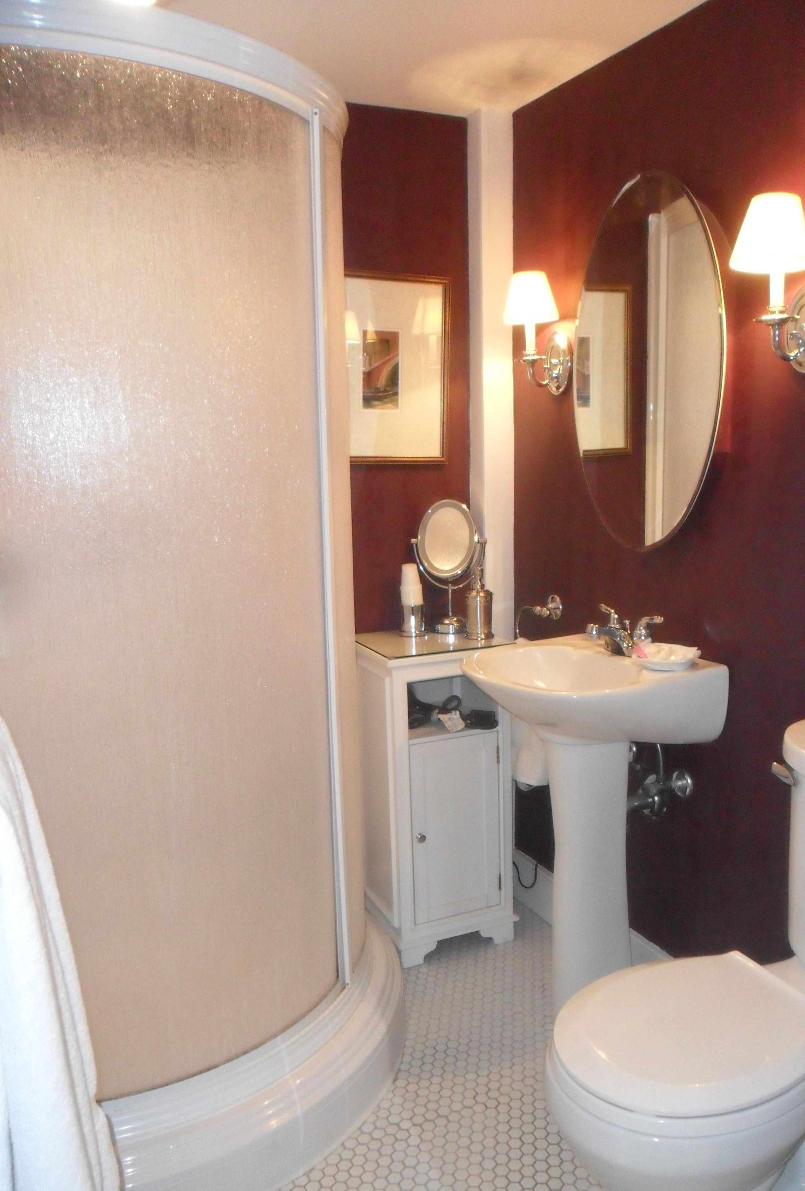 Une salle de bain avec des toilettes blanches, un lavabo, un miroir et une cabine de douche.