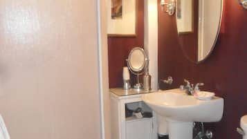 Une salle de bain avec des toilettes blanches, un lavabo, un miroir et une cabine de douche.