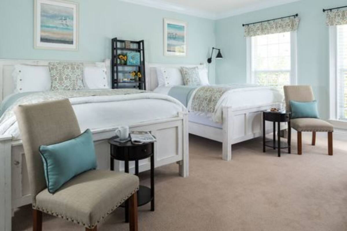 A bedroom with two beds, a chair, a small table, and a bookshelf.