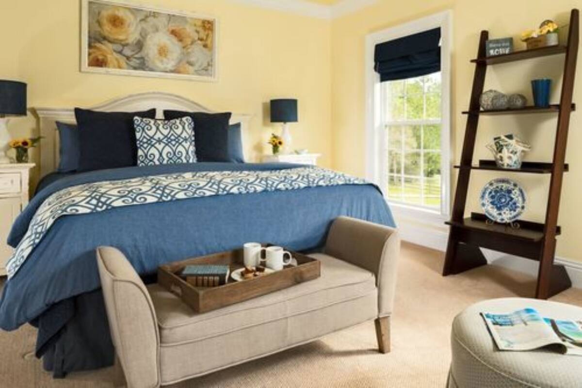 A bedroom with a bed, bedside tables, a bench, a ladder shelf, and a window.