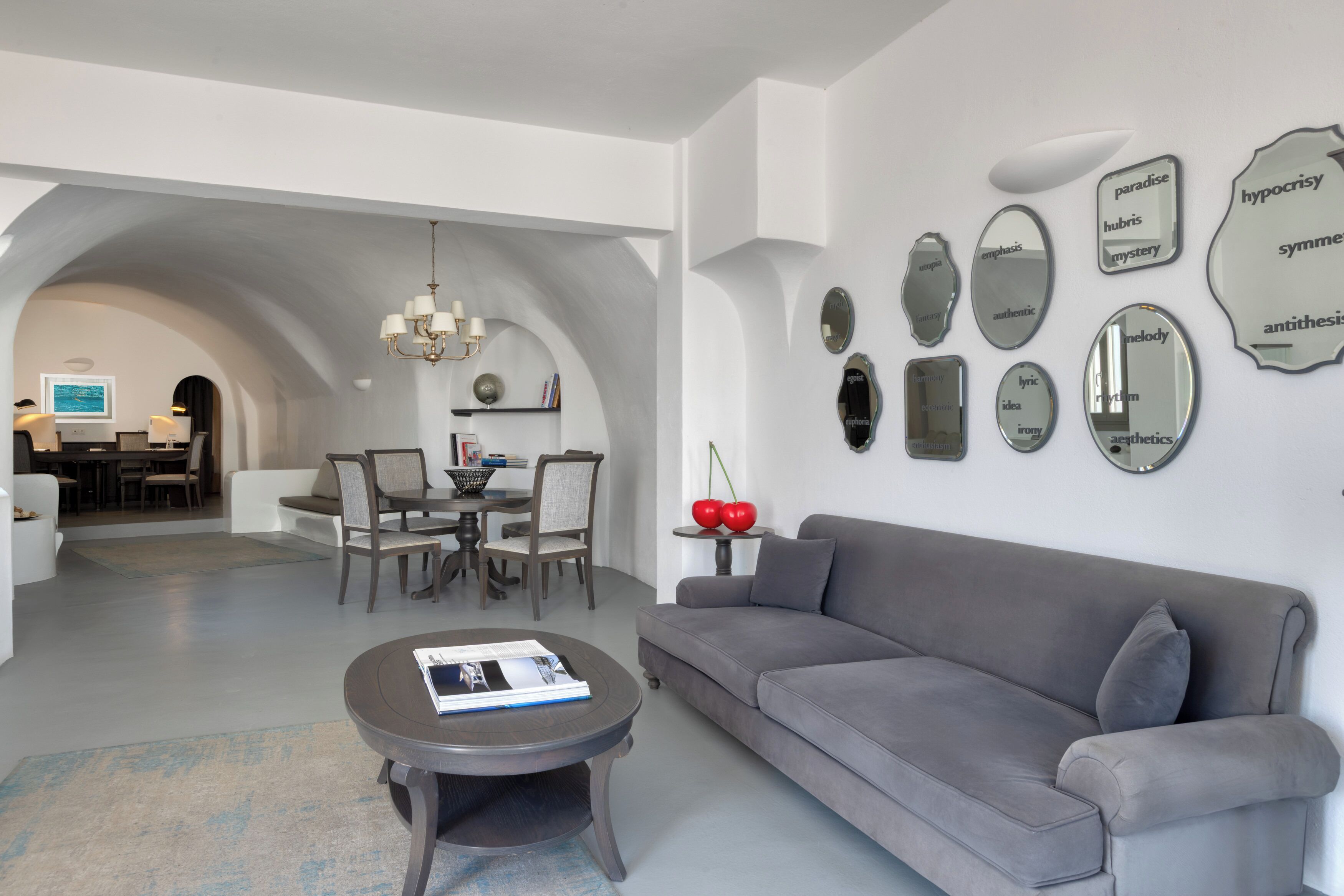 Ein modernes Wohnzimmer mit grauem Sofa, einem Couchtisch und einem Essbereich mit Stühlen und einer Chandelier.